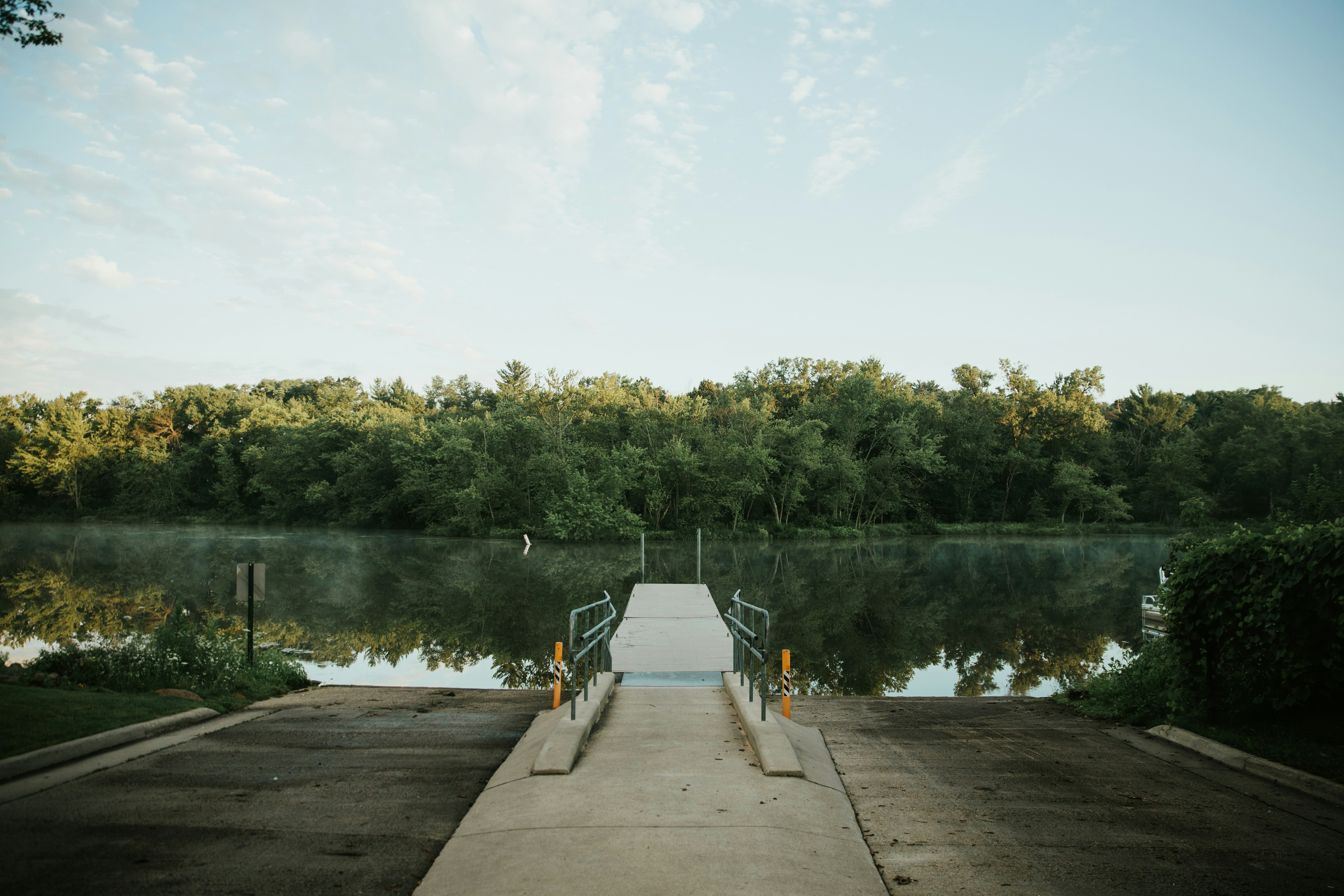 person in gray jacket standing on dock during daytime